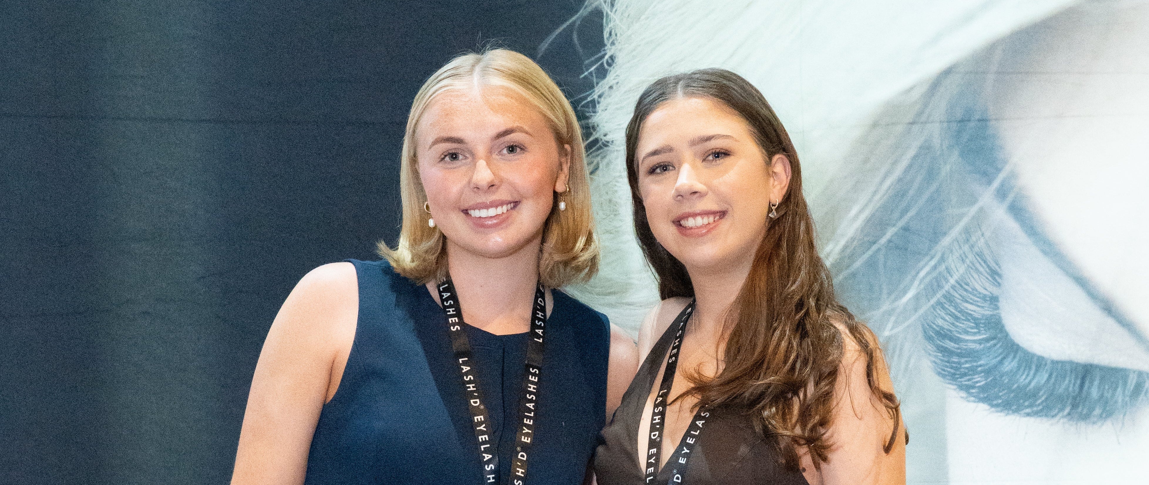 Two women standing behind a display of products with 'runway Lash Co.' branding in the background.