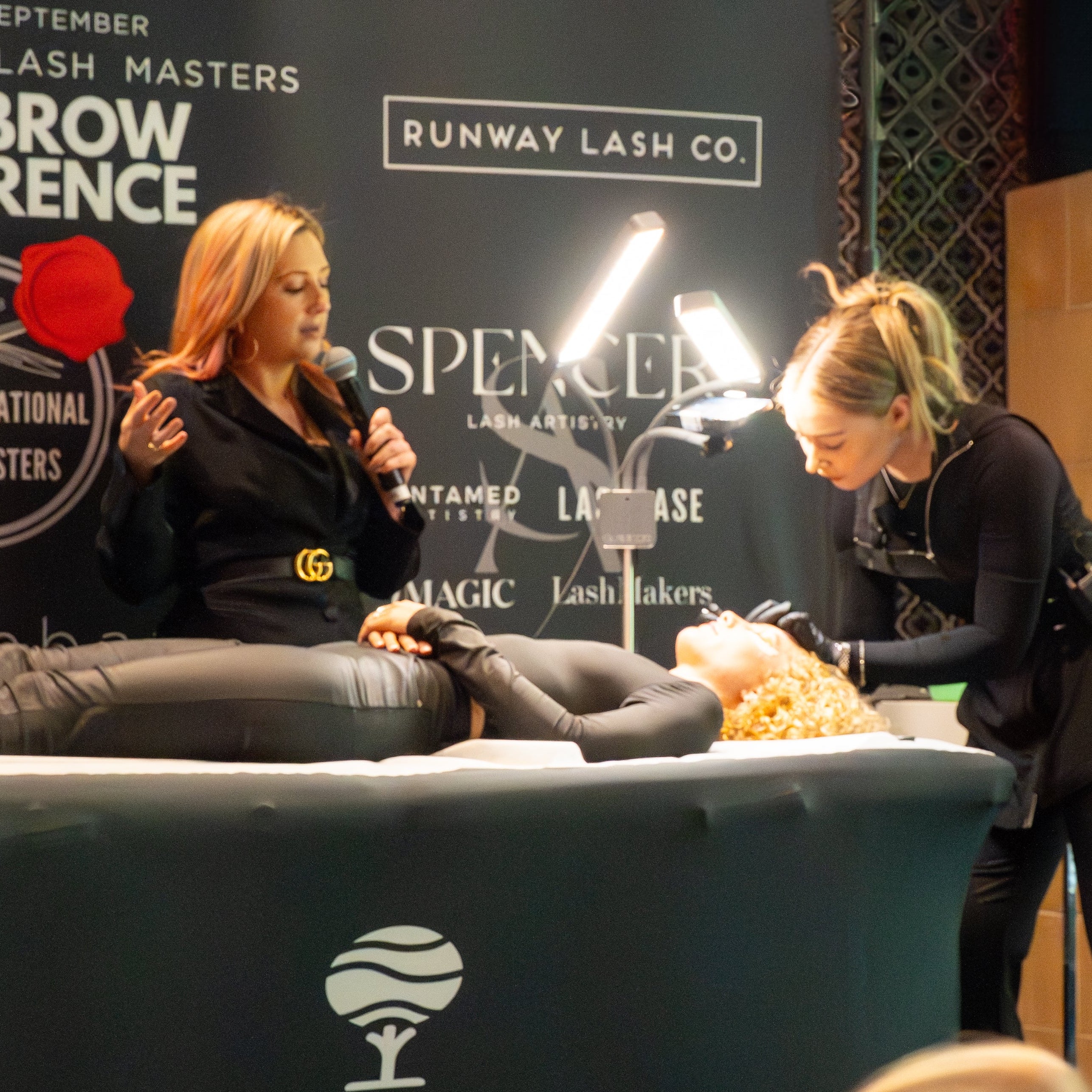 Woman receiving lash treatment at a lash and brow conference with 'elleebana' branding.